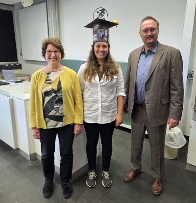 group picture of Prof. Brigitte Voit, Ronja Thümmler, Prof. Andreas Fery, the person in the middle wearing a mortarboard