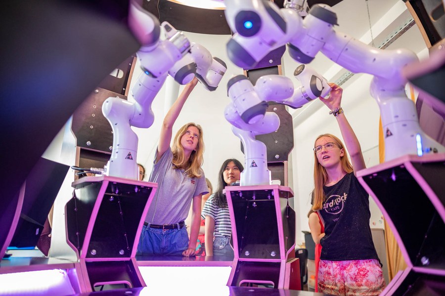 a group of young girls is interacting with some robots