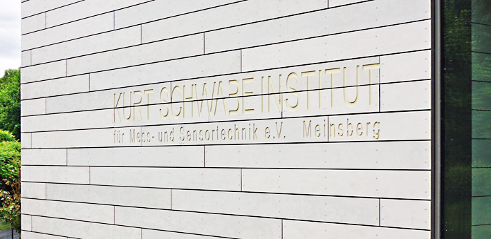 picture shows the wall of a modern building with the lettering 'Kurt-Schwabe-Institut für Mess- und Sensortechnik Meinsberg e.V.'